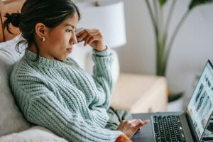 woman sitting in a chair looking in her laptop power of review marketing and localized seo